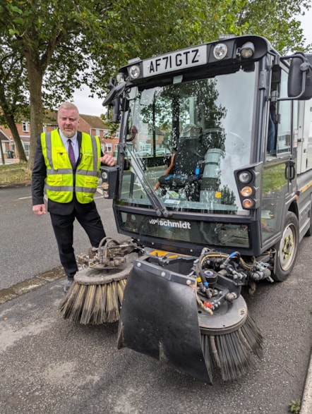 Cllr Damian Corfield with the roadsweeper carrying the new weed ripper arm