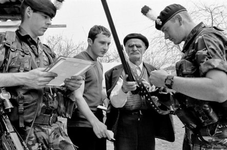 Four men gathered round a rifle - two are in military uniform.
