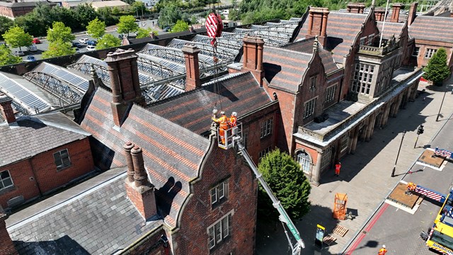 Engineers in a cradle removing a loose finial on Stoke station's roof