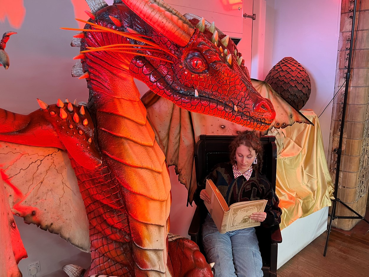 Fantasy at Leeds Central Library: Library and  Digital Assistant Heather Edwards reads a vintage copy of the fairytales of Hans Christian Anderson , illustrated by Kay Nielsen, while a dragon created artist Anne Stokes looks on.