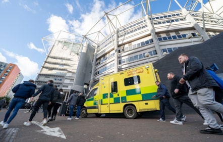 Ambulance outside St James' Park from low angle with people.