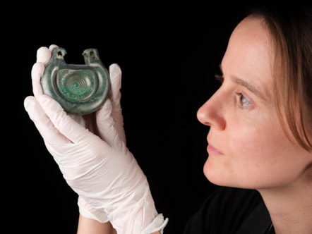 Conservator Bethan Bryan holds a bronze fitting. Photo © National Museums Scotland (2)