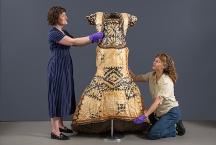 Curator Ali Clark and conservator Emma Pattinson prepares the barkcloth wedding dress for display. Photo © Neil Hanna