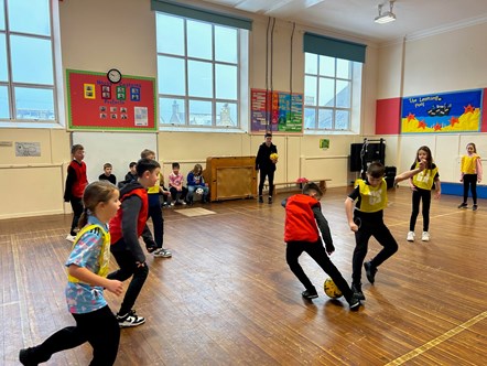 Jags midfielder, Marcus Goodall, watches on as p4 primary school pupils at Cluny Primary School have a game of football.