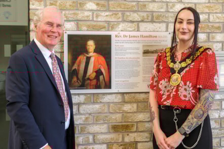 Mr James Gilchrist standing next Provost Claire Leitch in front of an information plaque about Rev Dr James Hamilton.