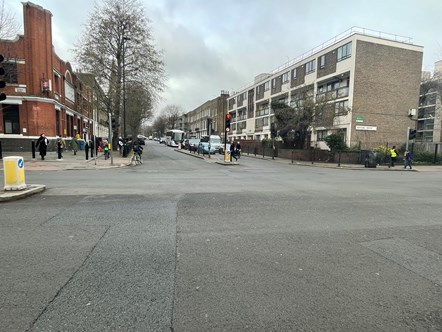 A picture of the New North Road and Essex Road junction, showing people walking, cycling, and driving in the area