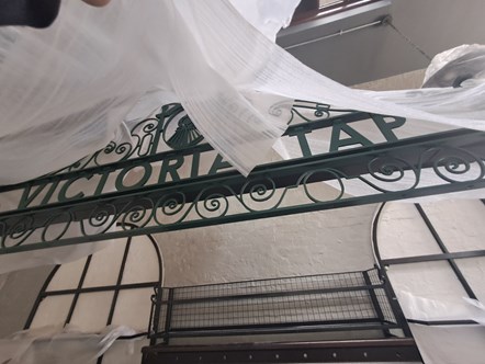 This image shows the sign at Victoria Tap at Victoria station being unveiled
