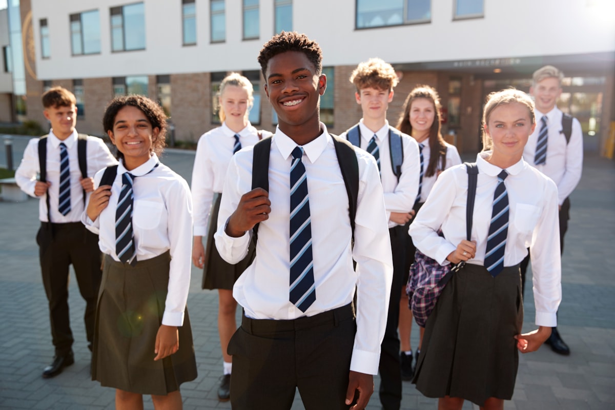 A diverse group of pupils in uniform standing together outdoors