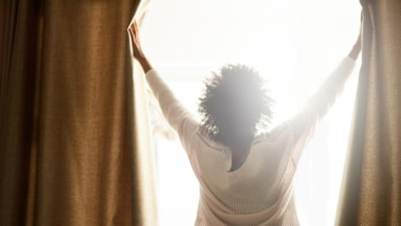 Woman opening curtains