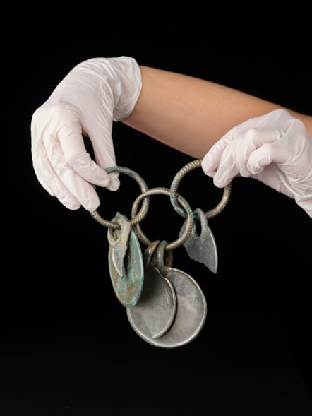 Conservator Bethan Bryan holds the bronze rattle pendant. Photo © National Museums Scotland (2)