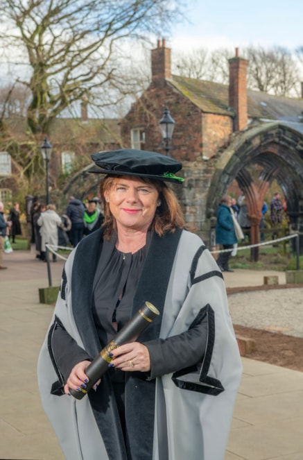 Michelle Skeer QPM OBE in academic robes outside Carlisle Cathedral after receiving an Honorary Fellowship from  University of Cumbria