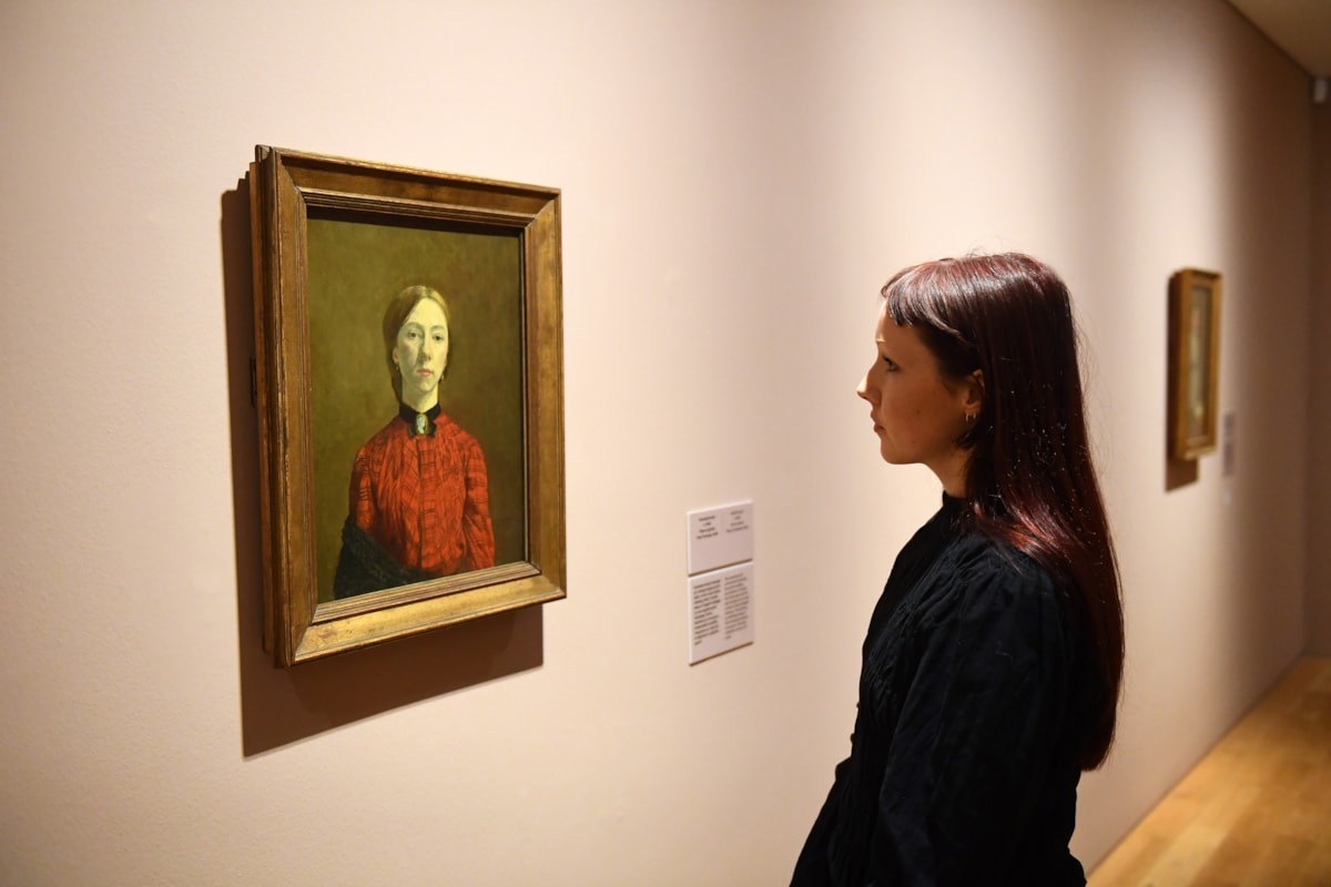 A young woman stands facing Self-Portrait, 1902, Gwen John, Tate. Photo credit Amgueddfa Cymru - Museum Wales