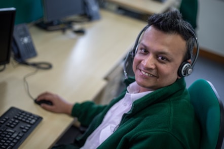 Portrait of Ehsanul Bhuiyan, smiling, sat at his desk in uniform and wearing a headset.