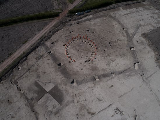 Wellwick Farm Archaeology Aerial Jul 2020: Credit: Infra Archaeology

Archaeologists stood on the outline of a horse-shoe shaped funerary enclosure, likely Iron Age in date. At Wellwick Farm, archaeologists believe the Bronze Age and Iron Age saw the addition of some domestic occupation with at least one roundhouse identified and possible structures such as animal pens and pits used for disposing food. 

Internal Asset No. 16776