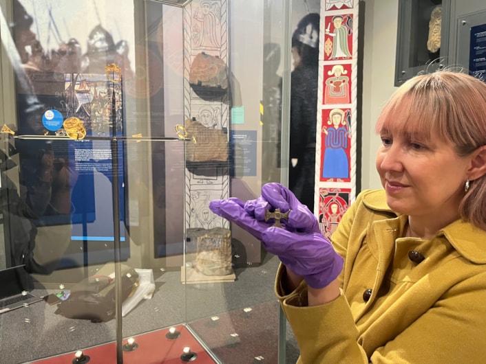 Saxon cross display: Curator of archaeology Kat Baxter with the ancient Saxon cross now on display at Leeds City Museum.
Believed to have once been a prestigious badge of office and a sign of religious identity, the silver, gilded pendant was discovered by a metal detectorist, with one of its four arms broken, and its central stone missing.
Newly created drawings, penned by archaeological illustrator John Prudhoe, show how the complete cross could have looked with its thin layer of gold leaf shining and a beautiful central garnet.