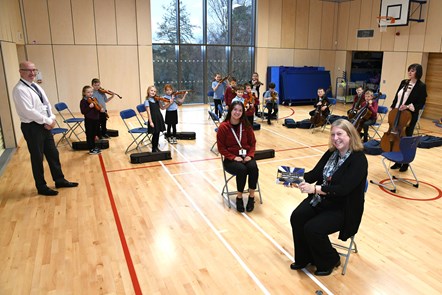 Julie Carrie (YMI Coordinator), Bellsbank PS Head Teacher Donald Currie with the Whole Class String orchestra