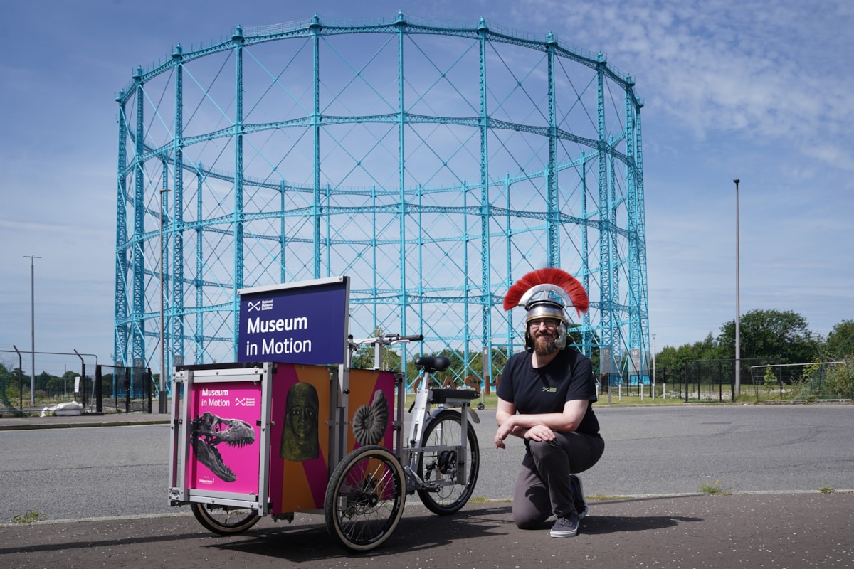 Enabler David Cree kneels beside National Museums Scotland's new cargo bike, Museum in Motion.