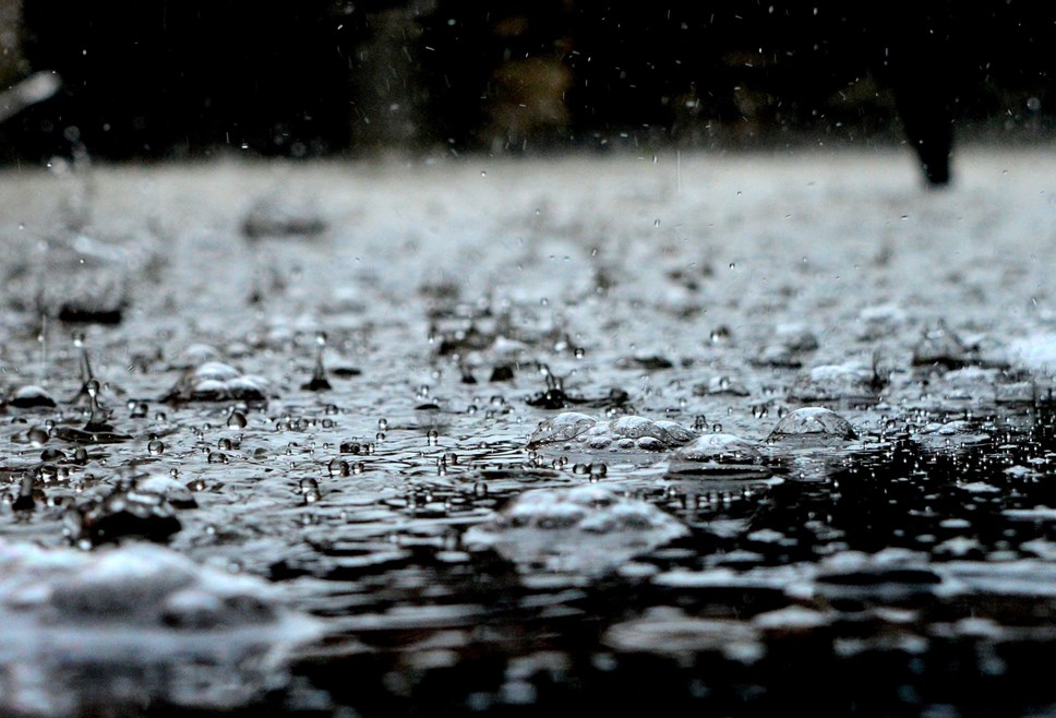 A close up picture of rain falling on a road and collecting as surface water.