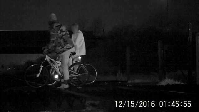Two people on bikes stop on the railway line at Griffin Lane level crossing