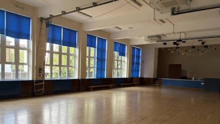 An empty, sunlit school hall with polished light-wood floring in the closed Oldhill Community School