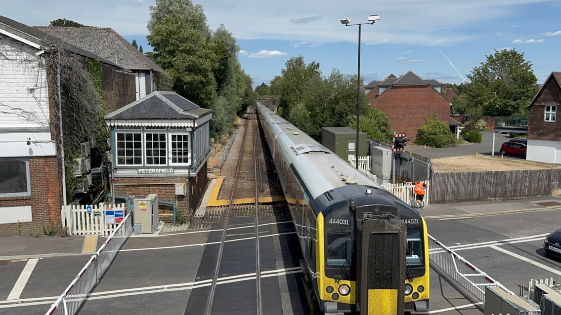 STARTING TOMORROW: Passengers urged to plan ahead during Portsmouth Direct Line works this February: SWR train passes over a level crossing heading into Petersfield station
