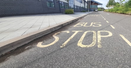 The image shows a bus stop in front of Elgin High School