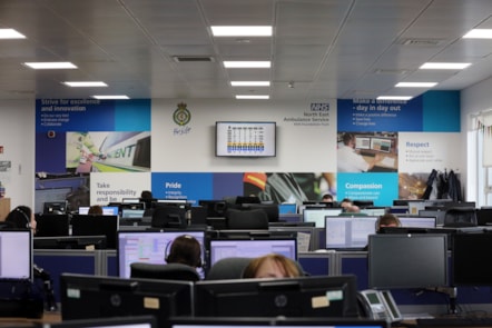 The Emergency Operations Room at NEAS with many computer screens and operators with headsets. The back wall of the room shows NEAS's values.