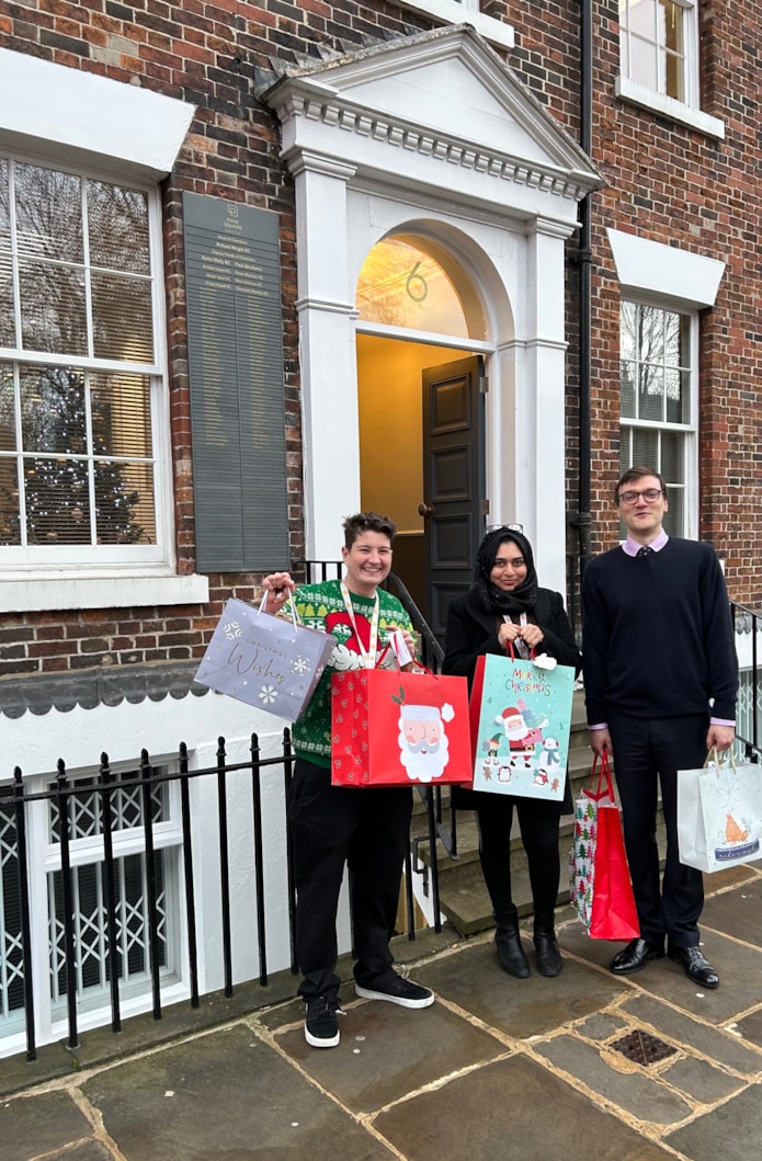 CFL Christmas Gifting 3: Image shows three people standing outside an office, holding gift bags.