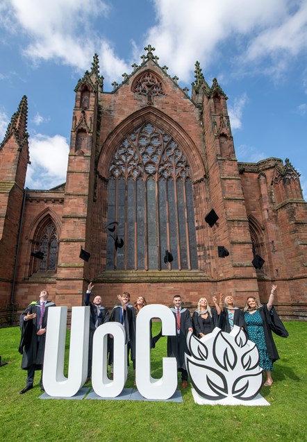 Graduates outside the East window of Carlisle Cathedral throw their mortar boards to celebrate their graduations
