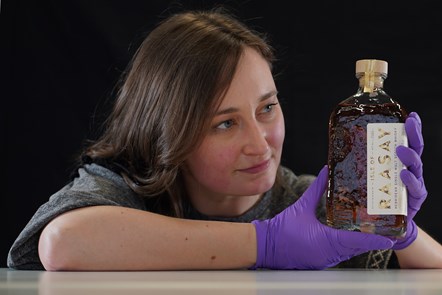 Doctoral Researcher Laura Scobie, with a bottle of whisky from Isle of Rasaay Distillery acquired by National Museums Scotland.Photo © Stewart Attwood.