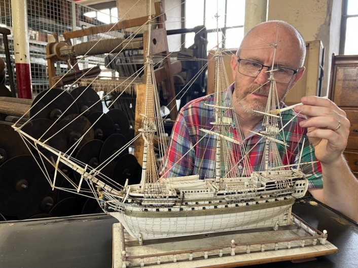 Model ships: Curator John McGoldrick with an intricate model ship carved from bone by a French prisoner during the Napoleonic Wars.
Complete with an elaborate figurehead, planked deck and carved helm with a steering gear and compass box, the bone model dates from the early 19th century and is believed to be an example of the type carved by French captives held in British prisons and aboard ships.