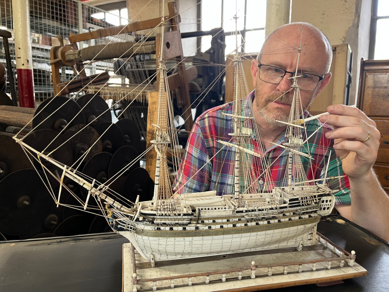 Model ships: Curator John McGoldrick with an intricate model ship carved from bone by a French prisoner during the Napoleonic Wars.
Complete with an elaborate figurehead, planked deck and carved helm with a steering gear and compass box, the bone model dates from the early 19th century and is believed to be an example of the type carved by French captives held in British prisons and aboard ships.