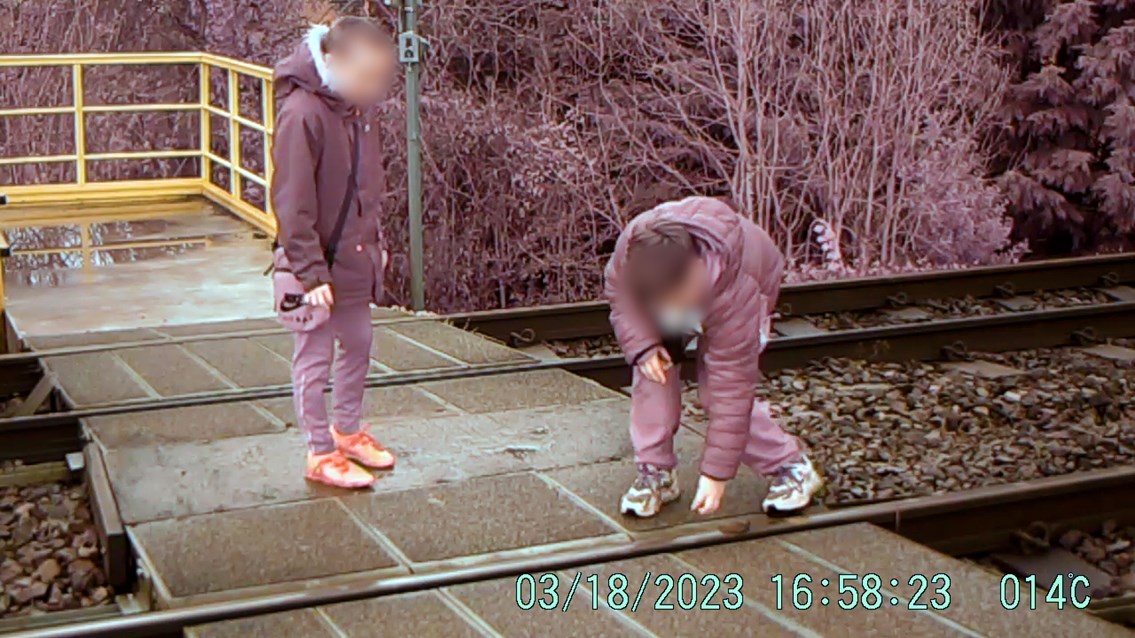 Two boys placing ballast stones on tracks so they are run over by trains