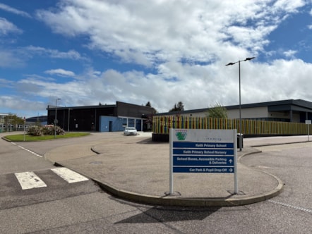 A photo of Keith Primary School, showing the school and the sign outside, which shows directions to the school, nursery, parking and drop-off area.