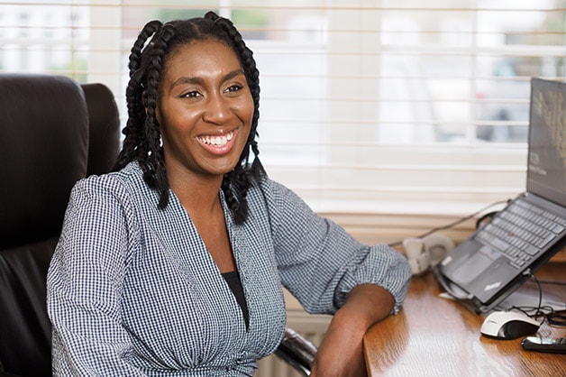 bame-scholarships-new-news-image: Woman sitting at her desk faces camera and smiles