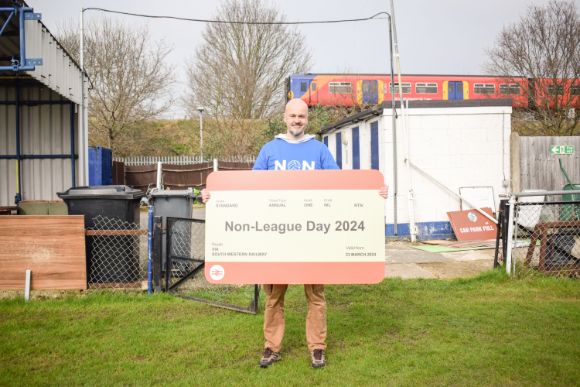 James Doe promotes Non League Day at Corinthian Casuals' ground in Tolworth as a  SWR Class 455 passes by