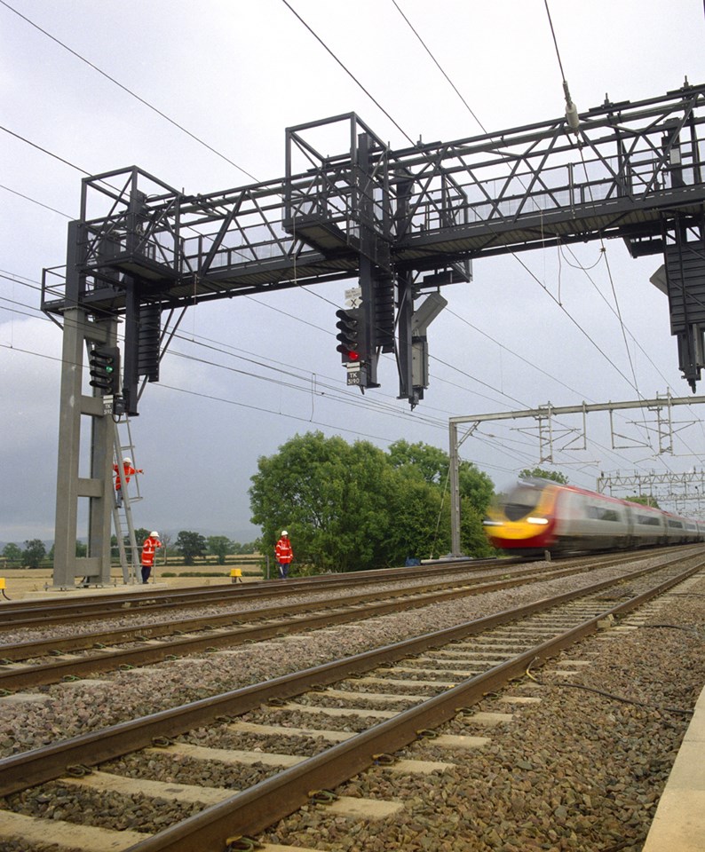 New signal gantry: New signal gantry on the West Coast Main Line with Pendolino passing and men working