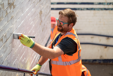 This image shows a volunteer painting the underpass at Starbeck station