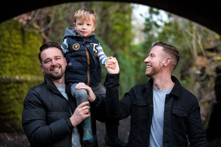 LGBT+ people in West Yorkshire urged to #BeTheChange by adopting a child or children who wait longer: Male couple muddy walk little boy on shoulder