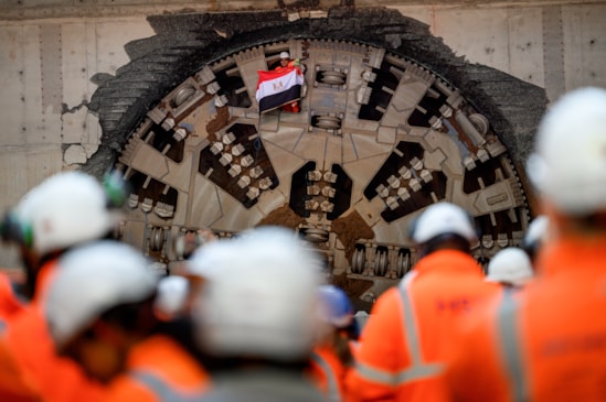 HS2 tunnelling miner holds flag of Eygpt through giant cutterhead of TBM Mary Ann after completing the breakthrough in Bimringham: The flags represent the nationality and regions of the expert tunnelling teams who have completing the tunnelling mission