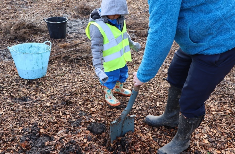 Cllr Turner helps a child with tree planting