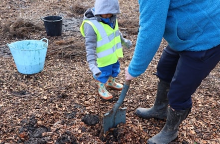 Cllr Turner helps a child with tree planting