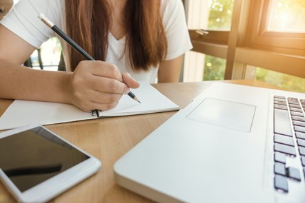 Woman writing by laptop