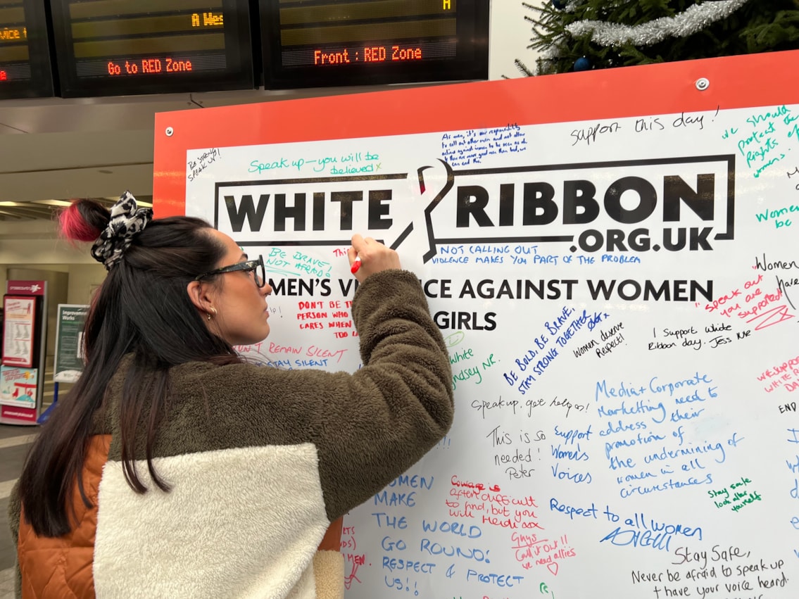 A member of the public signing the White Ribbon pledge wall at Birmingham New Street