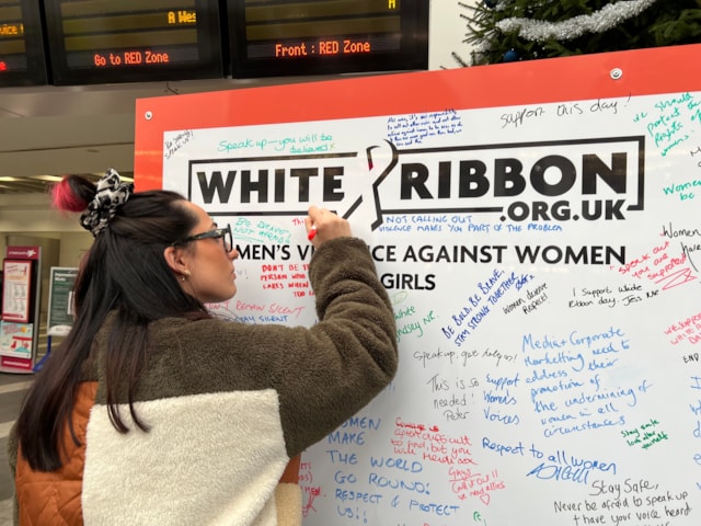 A member of the public signing the White Ribbon pledge wall at Birmingham New Street: A member of the public signing the White Ribbon pledge wall at Birmingham New Street