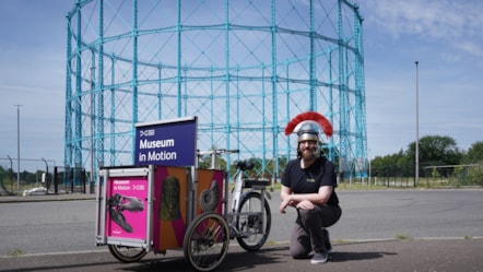 Enabler David Cree kneels beside National Museums Scotland's new cargo bike, Museum in Motion.