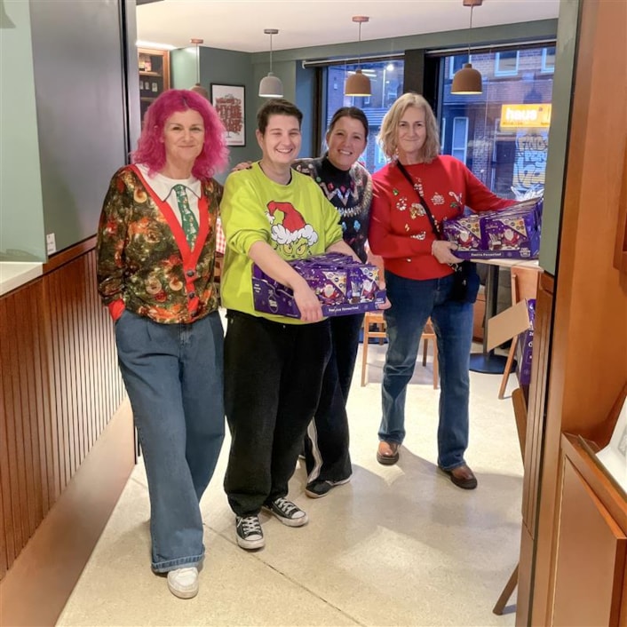 CFL Christmas appeal 2: Image shows people in a line, with Christmas jumpers, holding chocolate selection boxes donated for the appeal
