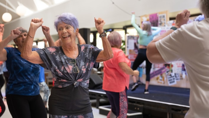 Neighbourhood networks 1: Image shows older people in a dance class, with an instructor on stage