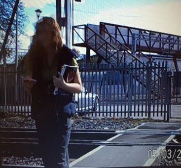 Report shows young adults in Brighton putting their lives at risk by using mobile phones while crossing the railway: Phone Smart - lady looking at phone with books in one hand, CCTV