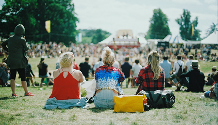three girls sat on the floor at a festival